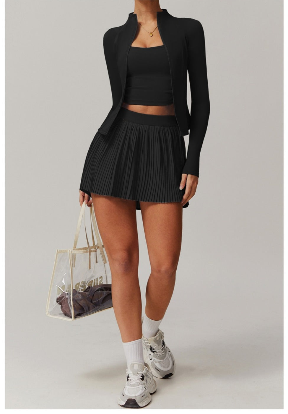 Person wearing a black outfit with a skirt and blazer, holding a clear handbag.