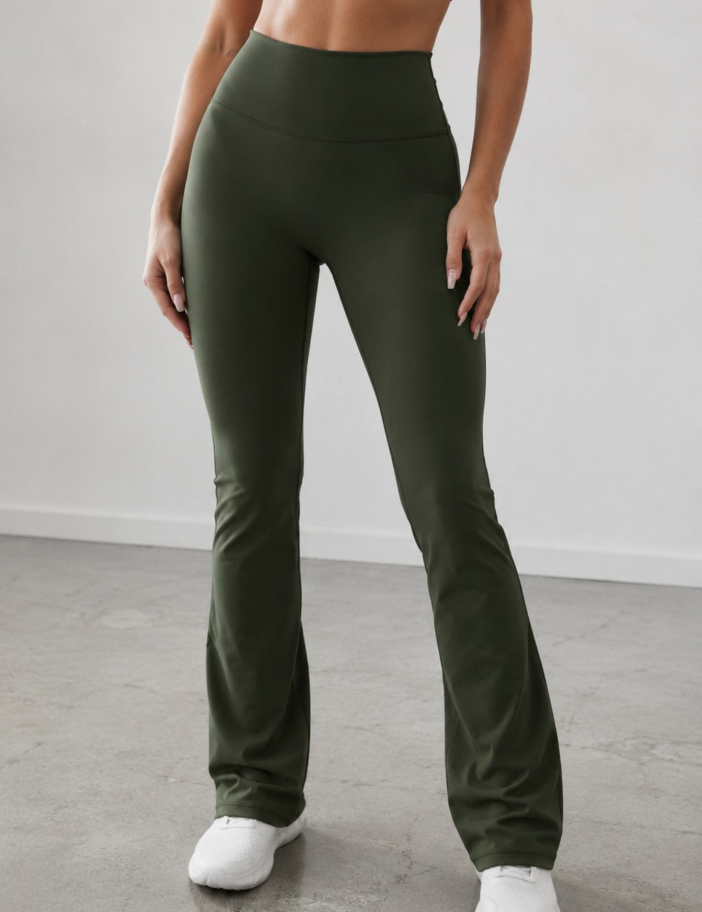 Person wearing olive green leggings and white sneakers on a plain background