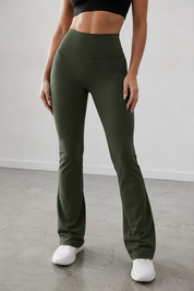 Person wearing olive green leggings and white sneakers on a plain background