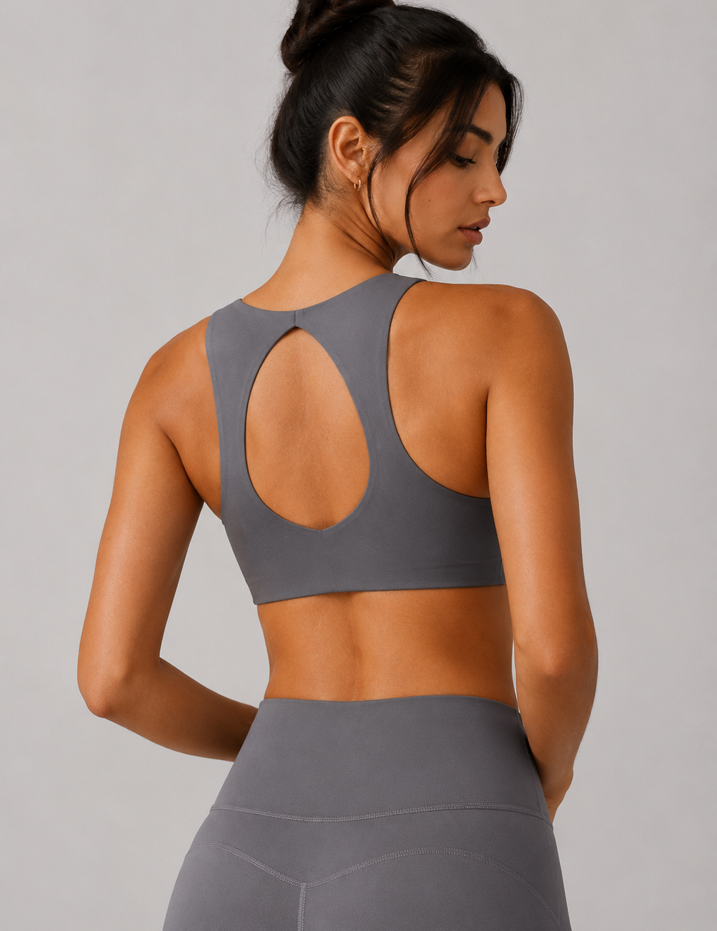 Woman wearing a gray sports bra and leggings against a plain background