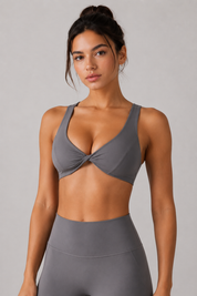 Woman wearing a gray sports bra and leggings on a plain background