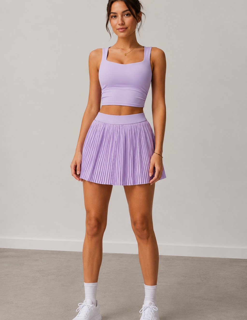 Woman wearing a purple athletic outfit with a skirt on a plain background