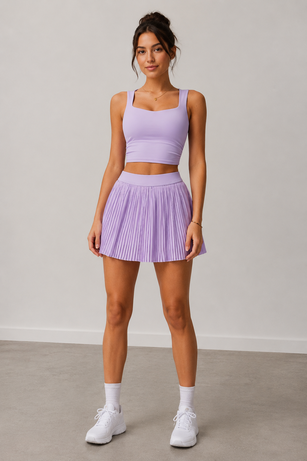 Woman wearing a purple athletic outfit with a skirt on a plain background