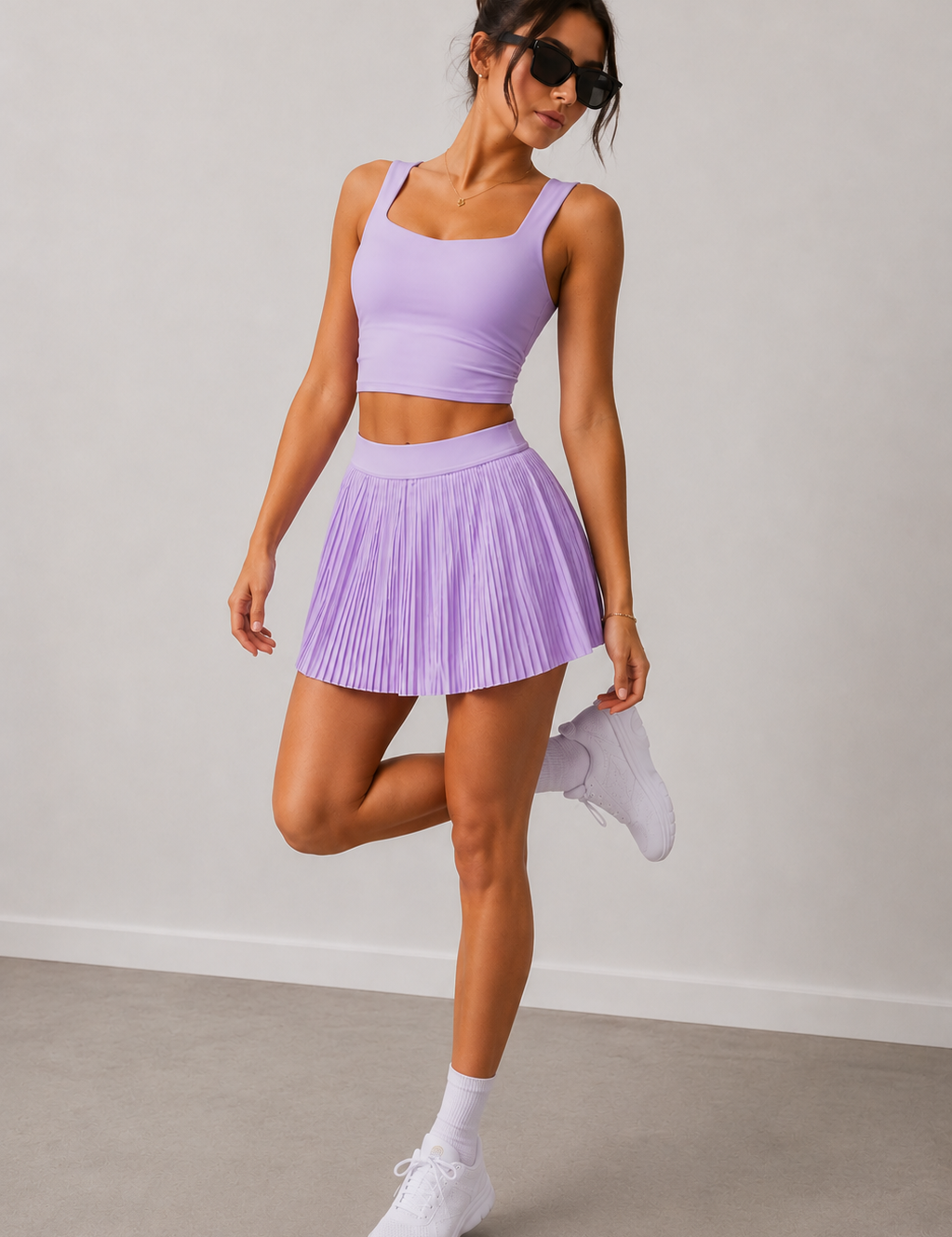 Woman wearing a purple athletic outfit with a skirt and top, standing against a plain background.