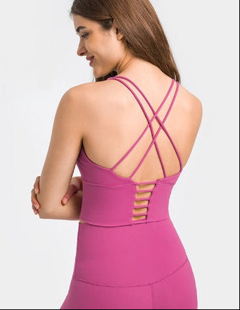 Woman wearing a pink athletic outfit with criss-cross back design on a white background